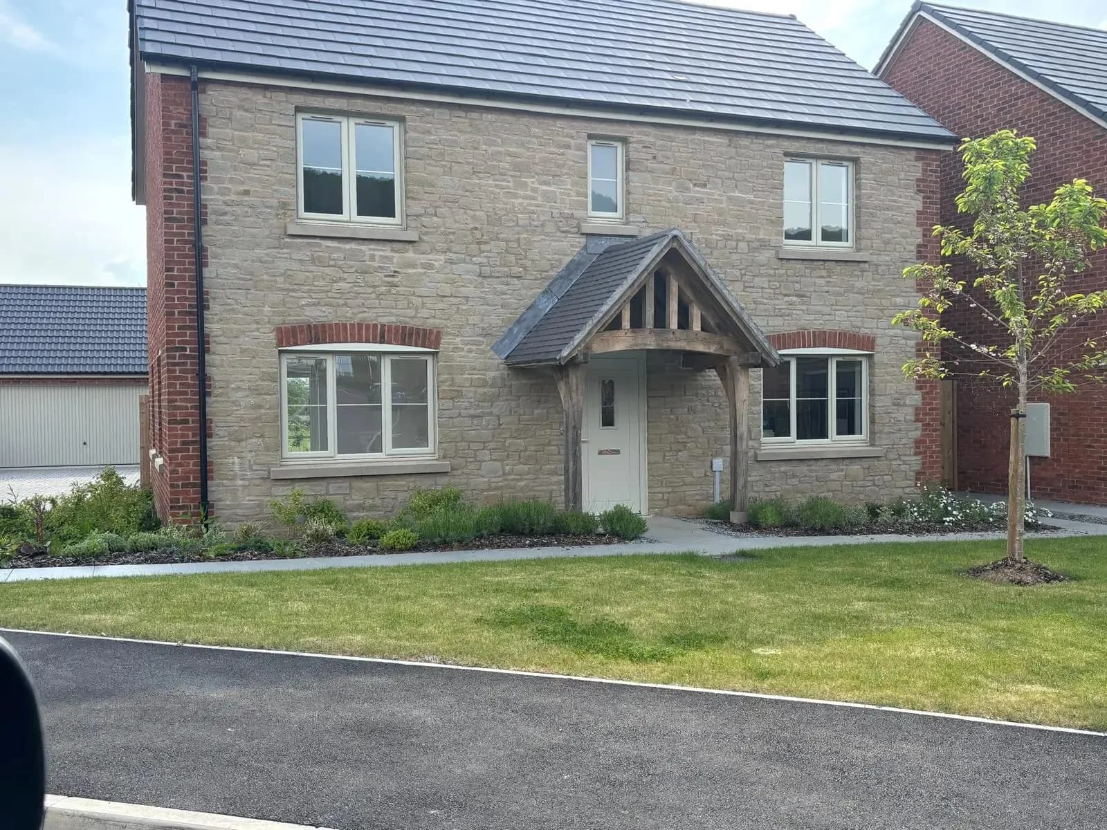 A new house faced in stone with brick quoins and an oak porch, Monmouthshire